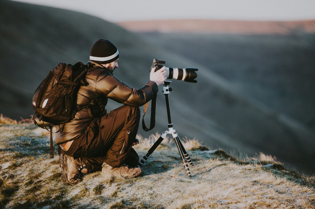 A photograph of another photographer taking a landscape picture from atop a small mountain