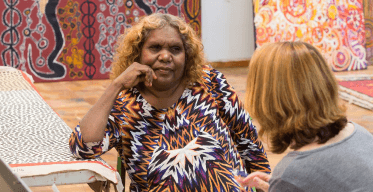 Photo of Aboriginal woman artist getting advice from lawyer in a room with paintings