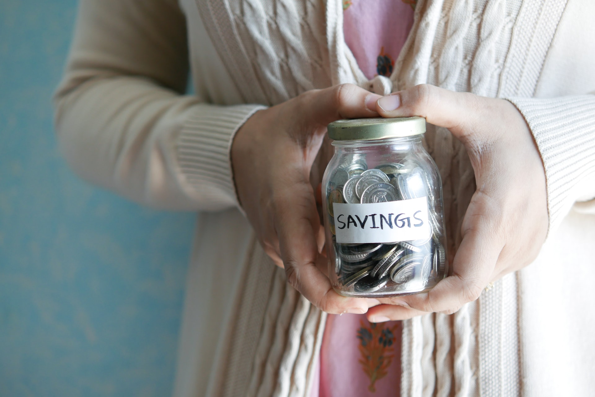A woman holding a jar of coins labelled savings