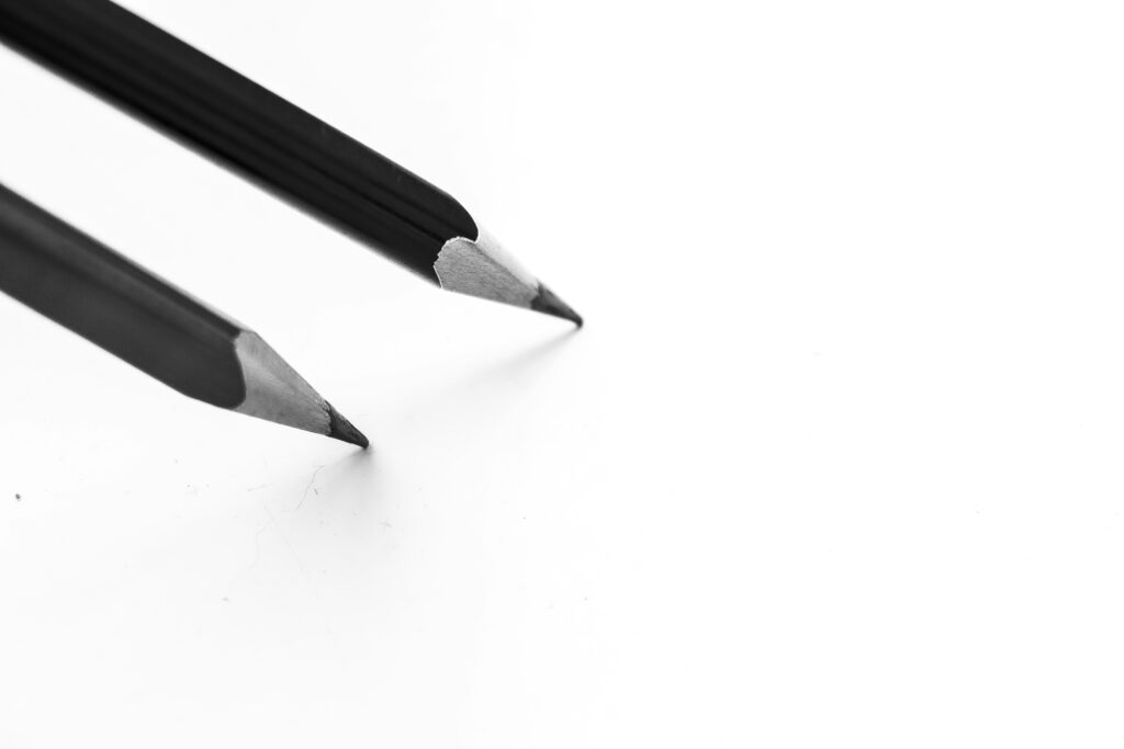 Two graphite pencils touching a clean sheet of white paper.