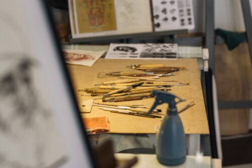 An artist studio, with a variety of artist's tools piled on a desk.