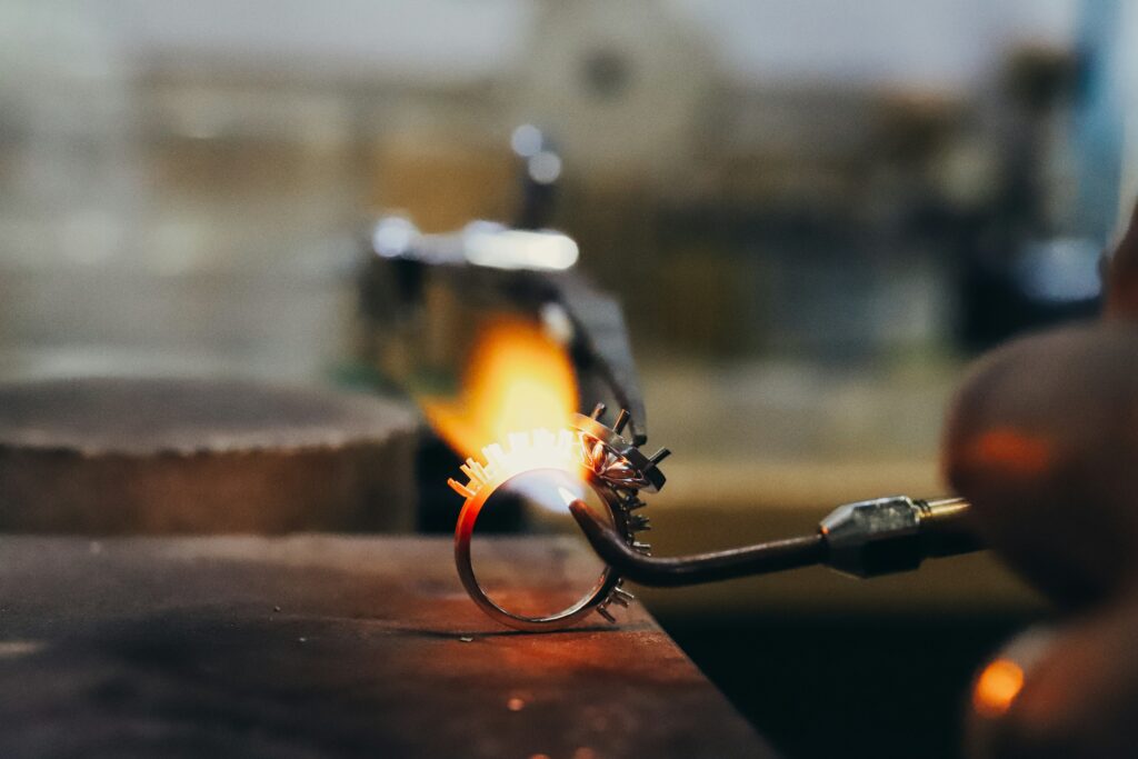 A close up of a ring detail being soldered with a flame.