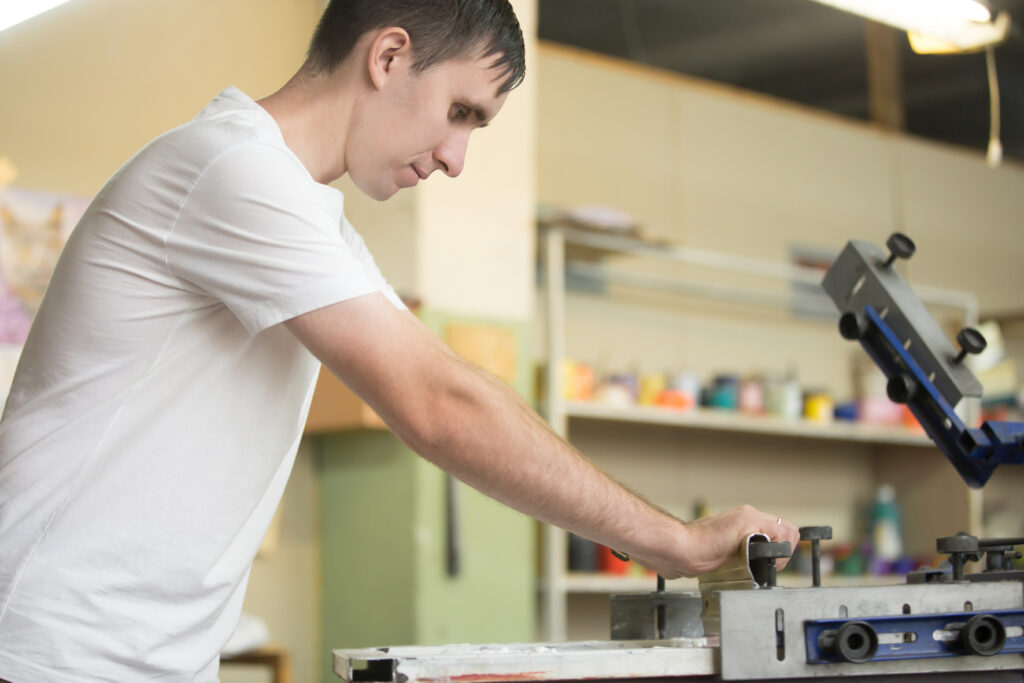 Young man working using printmaking tools, silk screen printing.